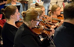 Violinist:innen in einem Orchester.