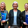 Veronika Cook-Jeltsch, Frauke Janz und Jana Steinbacher nach der Verleihung. Die Preisträgerinnen halten ihre Urkundenmappe und eine gelbe Rose in der Hand. Alle lachen freundlich in die Kamera.