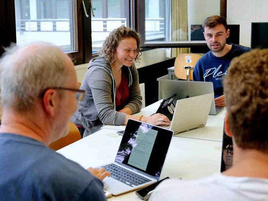 Zu sehen ist eine Gruppe Studierender mit einem Dozenten