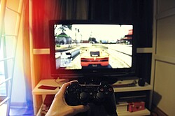Auf dem Bild sieht man einen Controller der vor einem Fernseher gehalten wird, wo ein Autovideospiel gespielt wird.