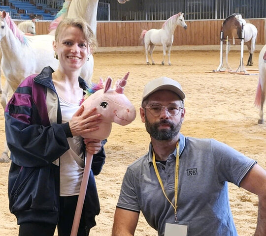Trainer Sebastian und Athletin Hanna auf dem Reitplatz - im Hintergrund Einhörner.