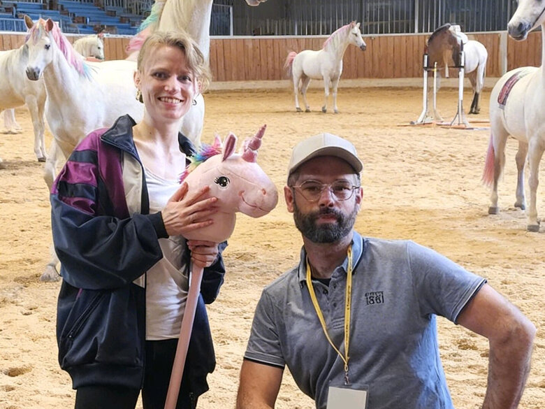 Trainer Sebastian und Athletin Hanna auf dem Reitplatz - im Hintergrund Einhörner.