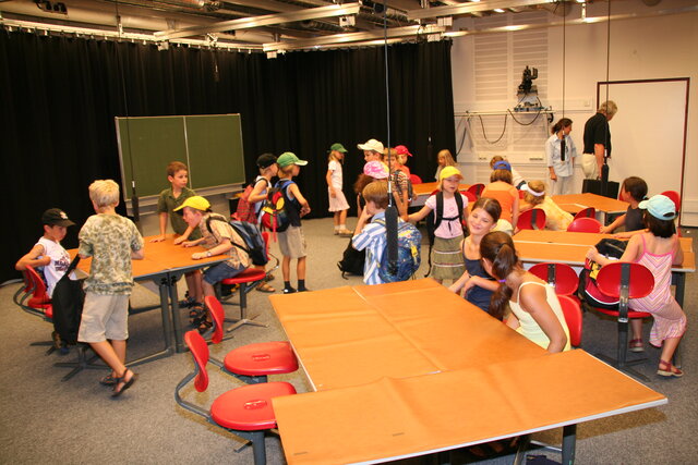 Viele Schüler an Tischen vor einer Videoaufnahme eines Unterrichts im Fernsehstudio im AVZ Neubau 