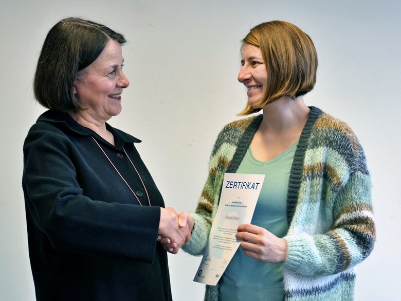 Professorin Dr. Jeannette Roos überreicht einer Teilnehmerin das Zertifikat der Weiterbildung "Qualifizierung zur Fachkraft Sprache und Kommunikation".