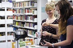 Das Bild zeigt zwei Frauen, welche gerade Kaffee in der Bibliothek ausschenken.