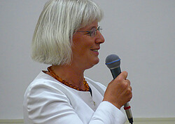 Frau mit Mikrofon in der Hand auf der Mitgliederversammlung.