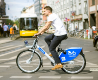 Person fährt mit einem VRNnextbike. Straßenbahn im Hintergrund