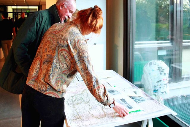 Zwei Professor:innen beugen sich über ein Kunstwerk. 