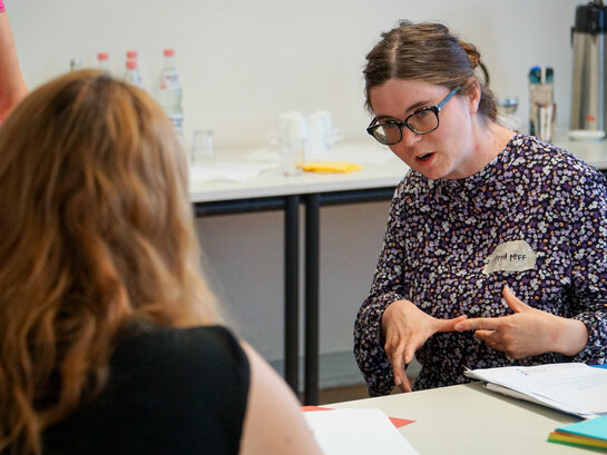Das Bild zeigt Anna Neff im Gespräch mit einer Person während eines Workshops.