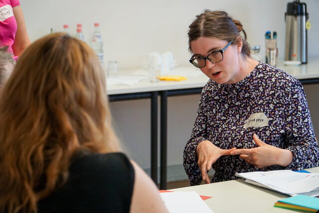 Das Bild zeigt Anna Neff im Gespräch mit einer Person während eines Workshops.