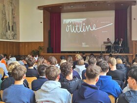 Das Foto zeigt eine Bühne vor der viele Kinder sitzen.