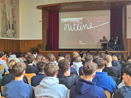 Das Foto zeigt eine Bühne vor der viele Kinder sitzen.
