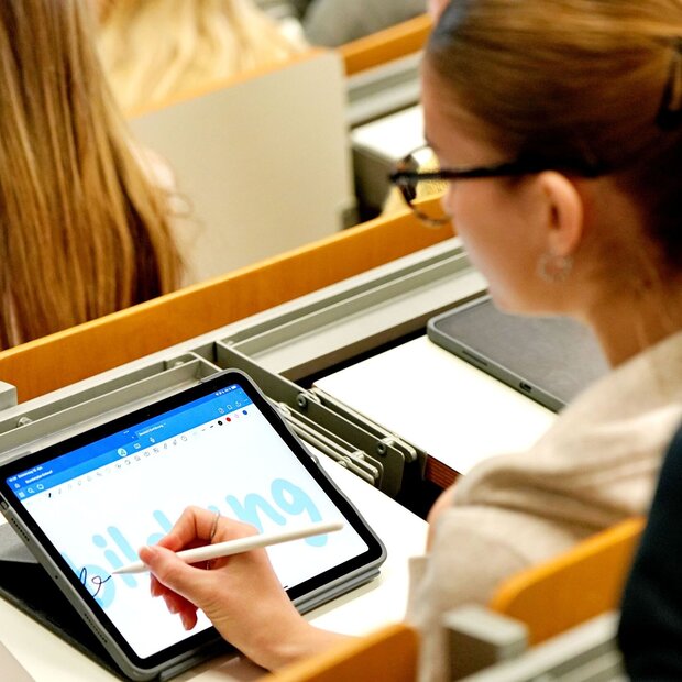 Eine Studentin sitzt im Hörsaal der Pädagogischen Hochschule Heidelberg. Sie schreibt "Bildung" auf ihrem Tabletbildschirm.
