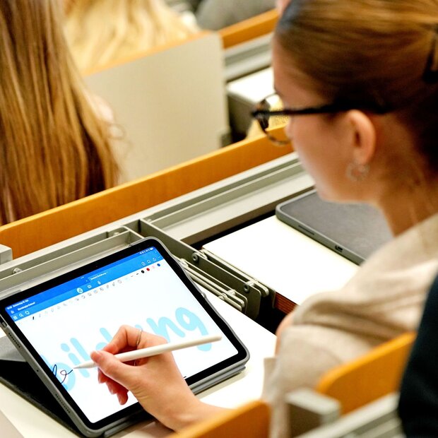 Eine Studentin sitzt im Hörsaal der Pädagogischen Hochschule Heidelberg. Sie schreibt "Bildung" auf ihrem Tabletbildschirm.