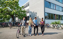 vier Personen vor der Hochschule Karlsruhe. 