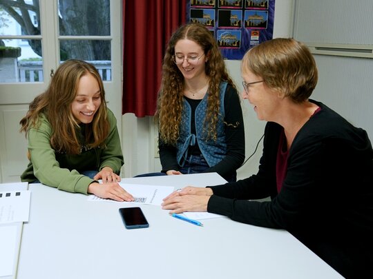 Zu sehen sind die Hilfskräfte Marlene Endrolath und Laura Klüven im Gespräch mit Antje Karbe aus der Kommunikation.