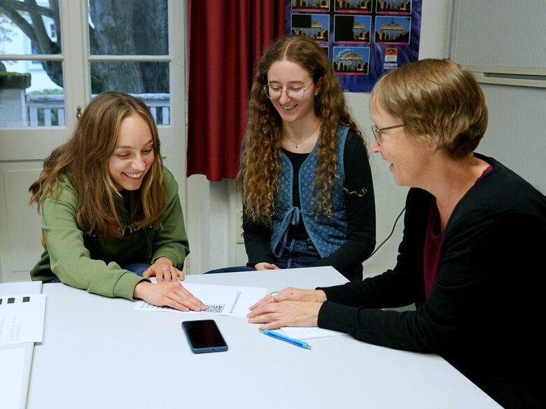 Zu sehen sind die Hilfskräfte Marlene Endrolath und Laura Klüven im Gespräch mit Antje Karbe aus der Kommunikation.