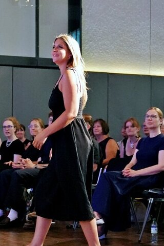 Zu sehen ist eine Alumna beim Betreten der Bühne.