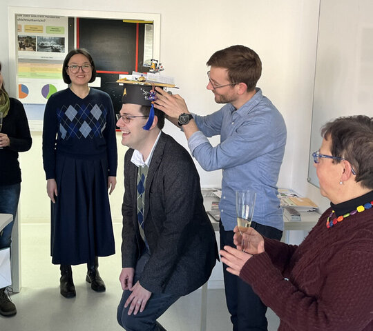 Foto der feierlichen Überreichung der akademischen Mütze an Andreas Spiziali durch einen Kollegen