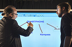 zwei Männer vor einer digitalen Tafel.
