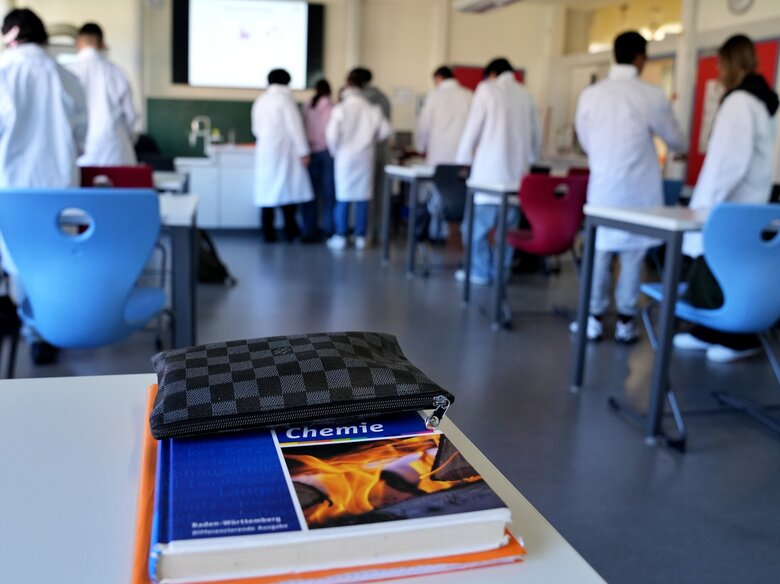 Das Foto zeigt eine Klasse beim Chemieunterricht, im Vordergrund ist ein Chemiebuch zu sehen