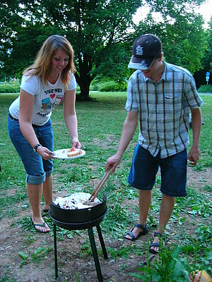 Mann überreicht einer Frau Essen am Grill