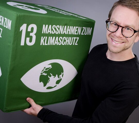 Zu sehen ist Johannes Rüd mit einem SDG-Würfel.