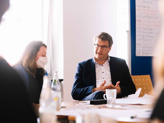 Perrson im Gespräch an einem Konferenztisch