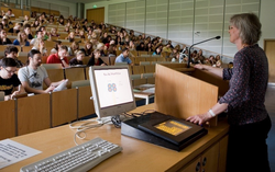 Hörsaal in dem viele Studierende sitzen und einer Dozentin zuhören. 