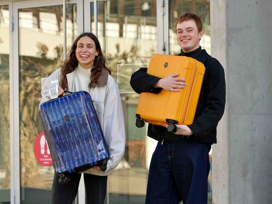Zwei Studenten stehen mit einem Koffer vor dem Neubau der Pädagogischen Hochschule Heidelberg.