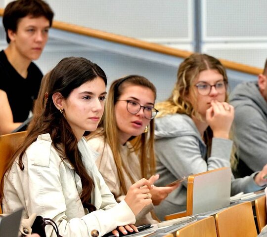 Studierende sitzen im Hörsaal und schauen nach vorne.