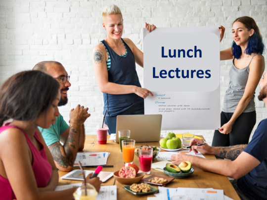 Votragende Person hält Poster vor sich, auf dem LunchLectures geschrieben steht