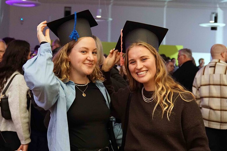 Zu sehen sind zwei Alumni der PHHD mit selbstgebasteltem Graduiertenhut.