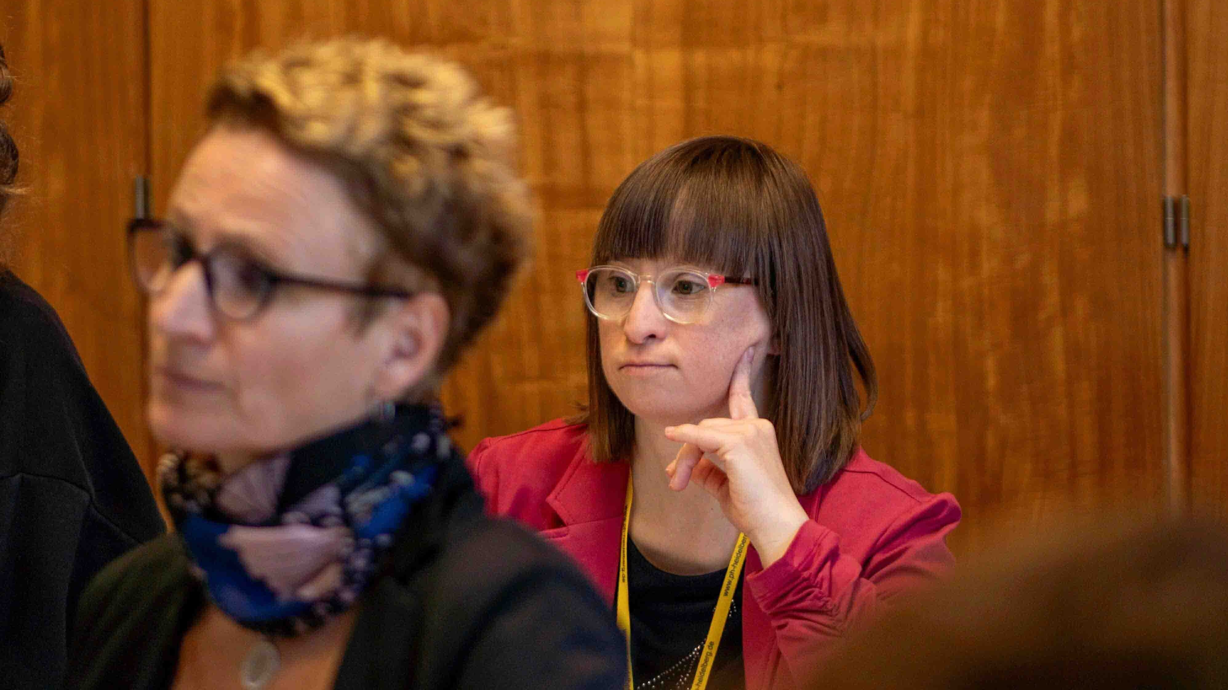Qualifizierungsteilnehmerin Susann Bensch verfolgt einen Tagungsbeitrag. Sie trägt eine Brille und stützt ihren Kopf in ihre Hand.
