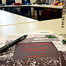 (c) Pädagogische Hochschule Heidelberg Buch mit Stift auf einem Tisch in einer Tischgruppe.