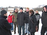 Gruppe in schneebedeckter Ebene, Häuser im Hintergrund