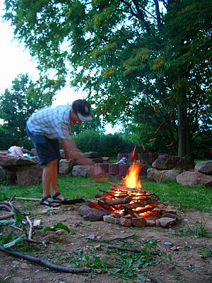 Mann legt Holz in Lagerfeuer