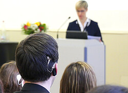 Studenten bei einer Vorlesung mit Cochlea- Implantat am Ohr.