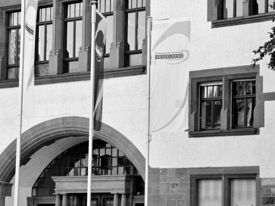 Das Schwarz-weiß Foto zeigt den Eingang des Altbaus der PH mit gehissten Flaggen.