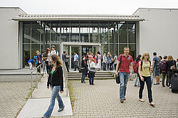 Studierende vor einem Eingang des Hörsaalgebäudes.