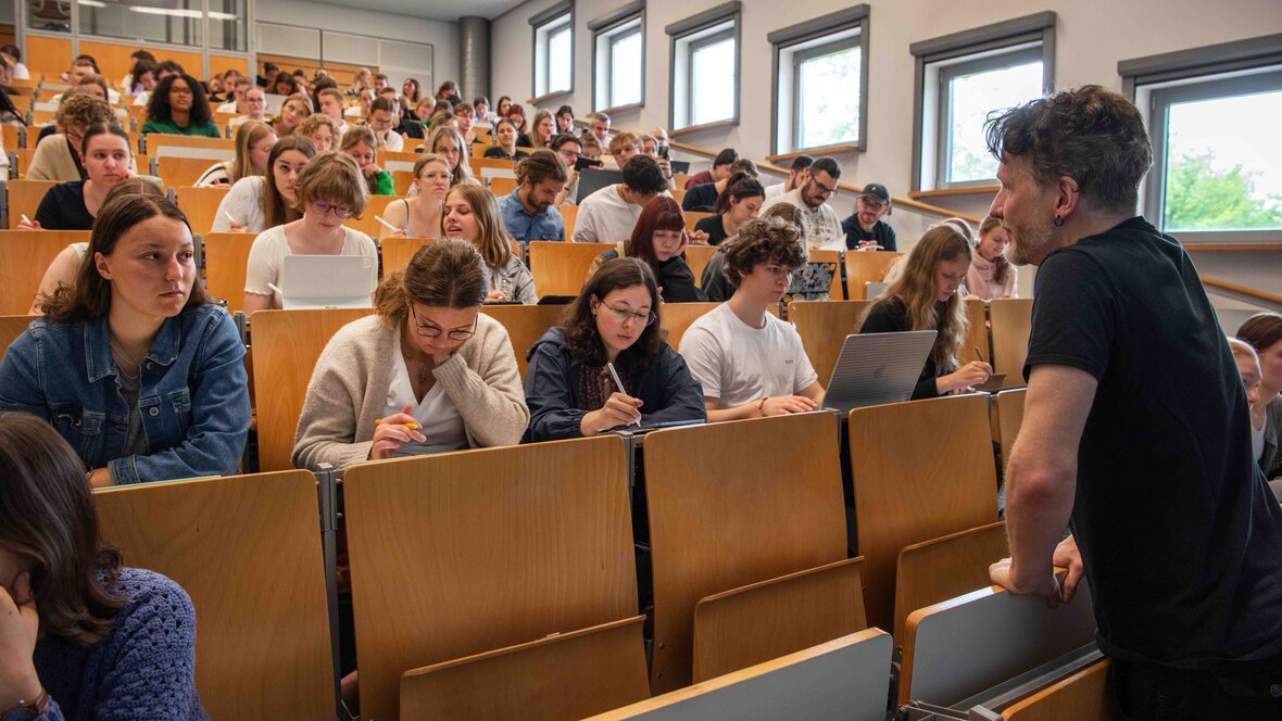 Ein Dozent hält vor einem vollen Vorlesungssaal im Hörsaalgebäude der Pädagogischen Hochschule Heidelberg eine Vorlesung.