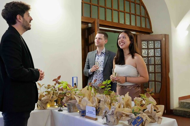 Zu sehen ist Max Wetterauer, wie er an der Pflanzenbar steht und Pflanzen als Erinnerungsgeschenk an Alumni ausgibt.