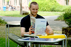 Das Bild zeigt einen Studenten. Er sitz im Innenhof der Hochschule. Er liest die aktuelle daktylos-Ausgabe. 