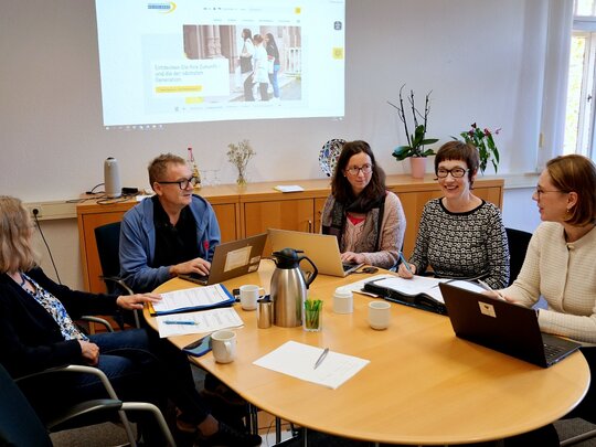 Zu sehen ist die Hochschulleitung arbeitend am Tisch