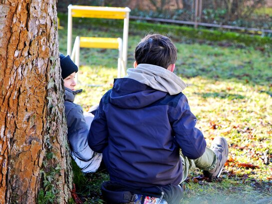 Das Foto zeigt zwei Kinder an einen Baum gelehnt.