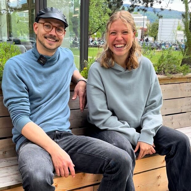 Der Tutor und die Tutorin der Sprecherziehung der Pädagogischen Hochschule Heidelberg sitzen auf einer Bank und strahlen in die Kamera.