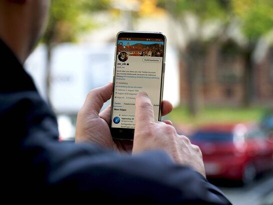 Das Bild zeigt eine Person mit einem Smartphone in der Hand.