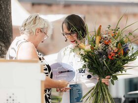 Theresia Bauer, Geschäftsführerin der Baden-Württemberg Stiftung und Wissenschaftsministerin a.D., überreicht Henrike Schön, Leiterin des Akademischen Auslandsamtes der Pädagogischen Hochschule Heidelberg, einen Blumenstrauß sowie eine Uhr.