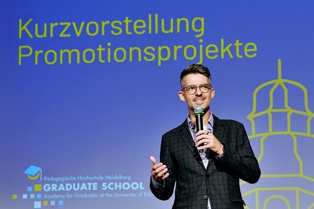 Zu sehen ist der Promovent Markus Knöpfel auf der Bühne stehend.