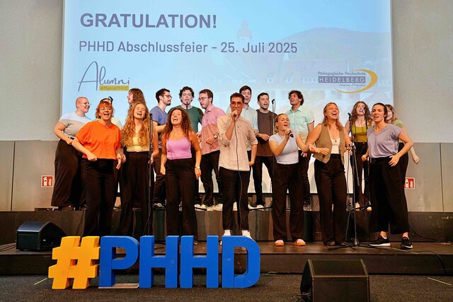 Zu sehen ist das Vokalensemble PolyPHonics der PHHD auf einer Bühne.